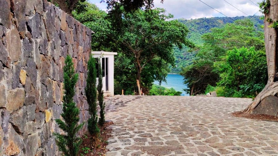 Muro de piedra volcánica y calle adoquinada con vista al lago